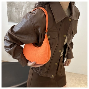 Bright orange crescent shoulder bag with crocodile pattern texture on a model side view