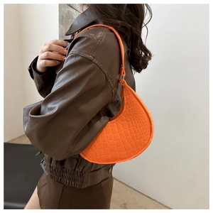 Vue détaillée du sac croissant orange vif avec motif crocodile et fine bandoulière d'épaule