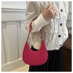 Detail of rose red crescent bag with crocodile pattern and zipper closure on a model