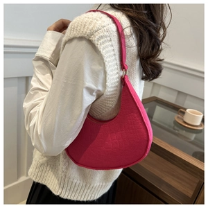 Détail macro du sac sous le bras en feutre rose magenta avec gaufrage crocodile porté
