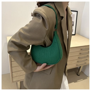 Green faux crocodile texture underarm bag styled on a brown blazer with gold metal buckle