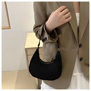 Detail of black faux crocodile leather crescent bag with elegant gold zipper accents