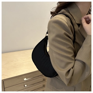 Close-up of black crocodile pattern hobo bag worn with a khaki blazer on the shoulder