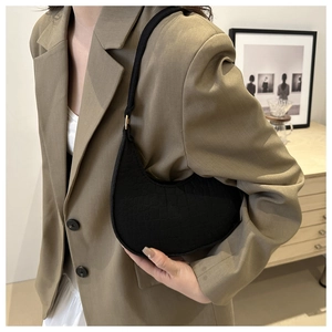 Detail van zwarte onderarmtas met steenpatroon gedragen op een kaki blazer