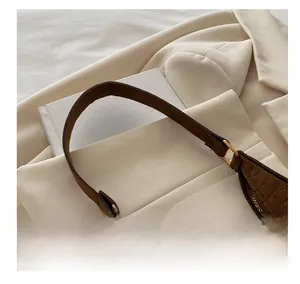 Close-up of brown crocodile embossed leather handbag with golden metal rings and sturdy handles