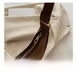 Detailed close-up of smooth gold zipper and crocodile embossed texture on a brown felt bag