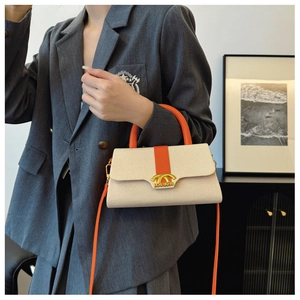 Detail der Box-Handtasche mit beigem Narbenleder, orangefarbenem Gurt und Goldverschluss