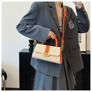 Detailansicht der Box-Tasche mit orangefarbenem Kontrastgriff und goldenen Beschlägen