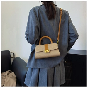 Detailansicht der beigen geflochtenen Handtasche mit braunem Leder und goldenem Verschluss
