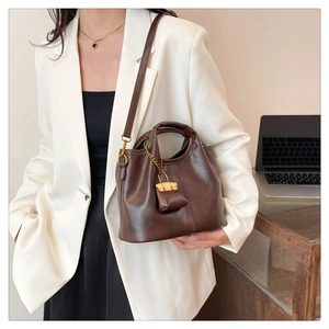 Detail of vintage dark brown leather tote with gold lock charm and crossbody strap