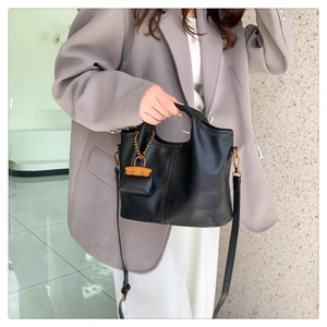 Chic black leather tote with metal chain detail shown on a stylish model in a blazer