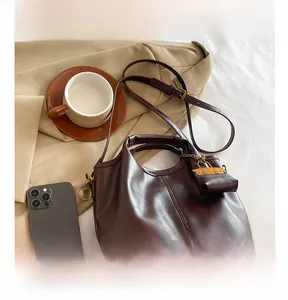 Detail of dark brown glossy leather tote with mini pouch charm and adjustable strap