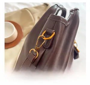 Detailed close-up of retro gold metal buckle and leather strap on dark brown handbag
