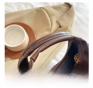 Close-up of wide PU leather handle and gold chain detail on vintage brown bucket bag