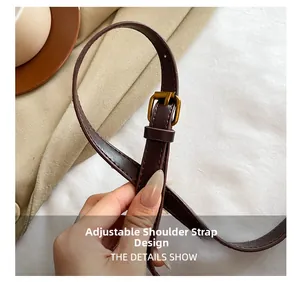 Detail of adjustable dark brown leather strap with bronze buckle on vintage bucket bag