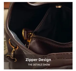 Detail view of smooth metal zipper and gold hardware on dark brown leather handbag