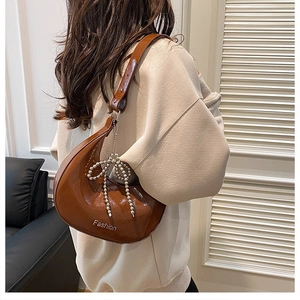 Detail of a brown hobo bag in glossy faux leather with beaded bow and Fashion logo
