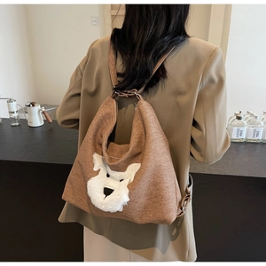 Détail de la bandoulière réglable et du patch chiot en peluche sur sac à dos marron