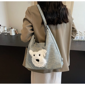 Détail du sac hobo en maille grise avec une décoration de tête de chiot en peluche