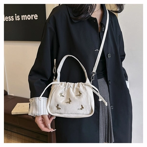 Détail du sac nuage plissé blanc crème avec charmes papillon dorés et fermeture à cordon