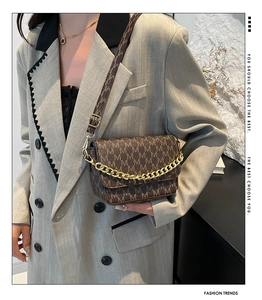Detailed view of brown letter-printed handbag with gold chain and leather strap