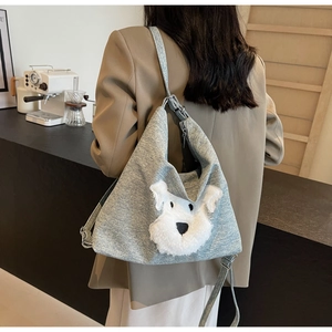 Détail d'un sac bandoulière gris avec écusson en peluche schnauzer sur un mannequin