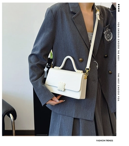 Detail of white leather shoulder bag with cloud-shaped clasp and wavy handle on a model