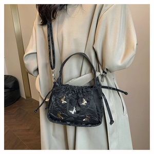 Fashionable black pleated bucket bag with silver butterfly appliques on model outfit
