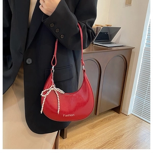 Detail of red glossy half-moon underarm bag with pearl bow charm and Fashion print