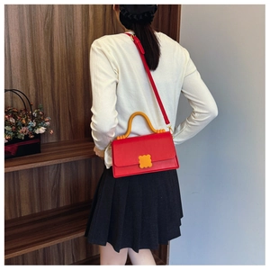 Model showcasing a luxury red and yellow contrast handbag with a stylish wave-shaped handle