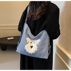 Détail de l'écusson schnauzer en peluche blanche sur un sac fourre-tout en denim bleu