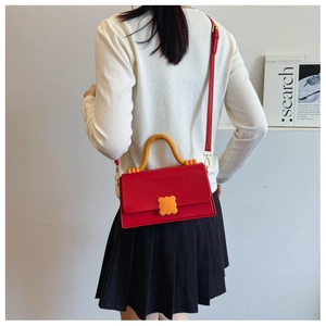 Model wearing a red contrast square crossbody bag with yellow wave buckle detail