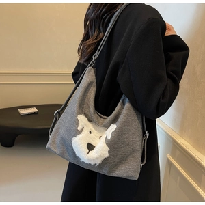 Détail du sac fourre-tout en toile grise avec applique de chiot en peluche blanche et bandoulière