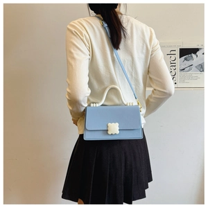 Back view of model wearing a light blue crossbody bag with unique white wavy handle