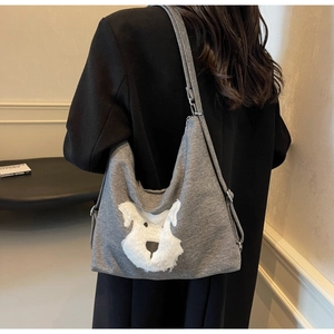 Détail du sac fourre-tout gris en tricot avec motif de chiot en peluche 3D sur l'épaule