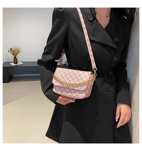 Detailed shot of pink crossbody bag with M-pattern and chunky gold chain strap
