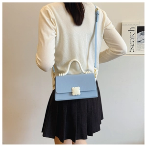 Rear view of a model wearing a light blue crossbody bag with a white U-shaped handle