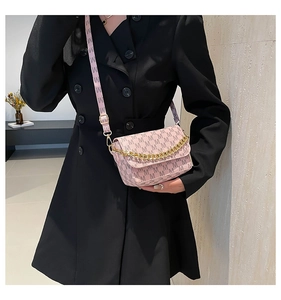 Detailed close-up of a pink crossbody bag with M-pattern print and chunky gold chain strap