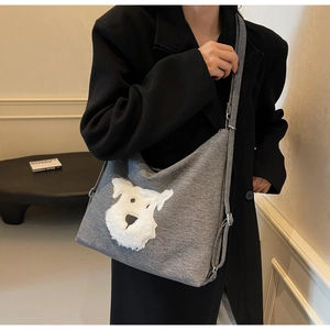 Detail of grey plush dog tote bag showing shoulder strap and fabric texture on a model