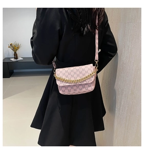 Close-up of pink monogram crossbody bag with gold chain and letter M print on model