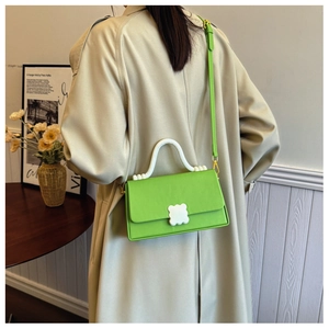 Apple green crossbody bag with wavy handle shown on model in a cozy indoor setting