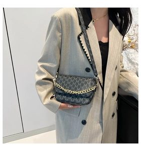 Detail of grey monogram crossbody bag with gold chain strap on a grey blazer outfit