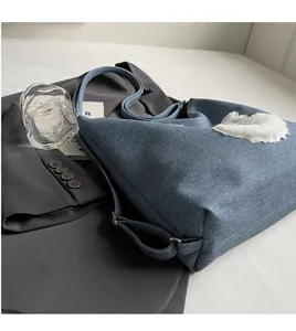 Detail of denim blue tote with white plush heart patch and smooth wide shoulder strap