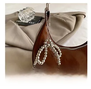 Detail of dark brown faux leather crescent bag with metallic silver bead bow charm