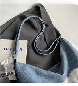 Detailed view of denim tote bag with white plush charm on a grey blazer background