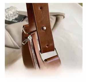Close-up of durable silver metal shoulder strap ring and stitching on brown cracked leather bag