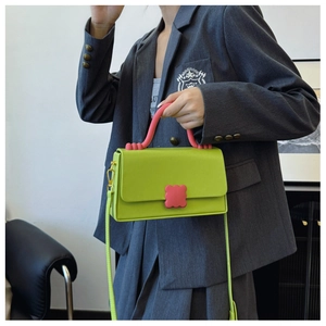 Detail of green PU leather handbag featuring a pink wave buckle and gold hardware