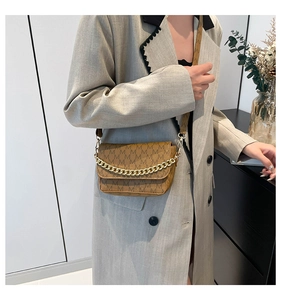 Close-up of brown crossbody bag with M-pattern print and chunky gold chain strap
