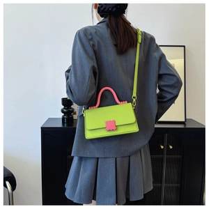 Close-up of bright green rectangular handbag with pink flower clasp and pink handle