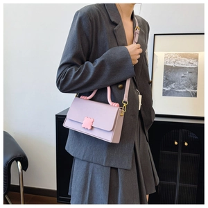 Detail of lavender purple crossbody bag with pink floral clasp on grey blazer